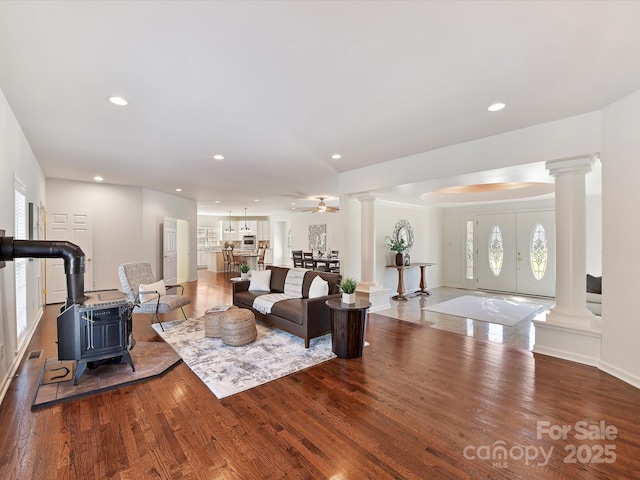 living room featuring hardwood / wood-style flooring, decorative columns, and a wood stove