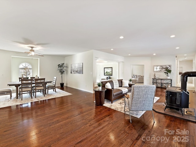 living room with hardwood / wood-style floors, ceiling fan, and a wood stove