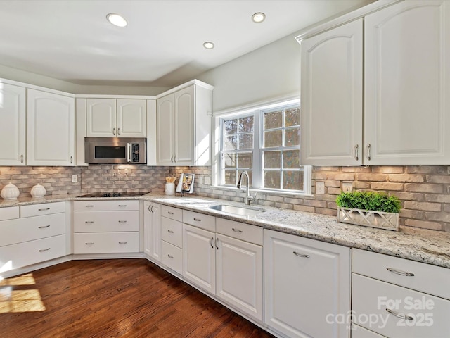 kitchen with sink, white cabinets, black electric cooktop, and decorative backsplash