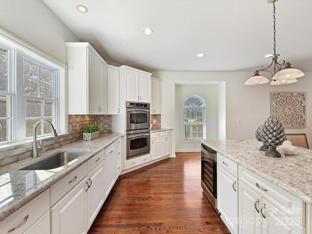 kitchen featuring pendant lighting, sink, wine cooler, white cabinets, and stainless steel double oven