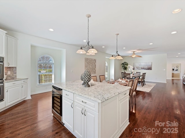 kitchen with pendant lighting, a center island, white cabinets, dark hardwood / wood-style flooring, and beverage cooler