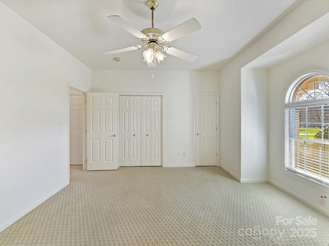 unfurnished bedroom featuring ceiling fan, light colored carpet, and a closet