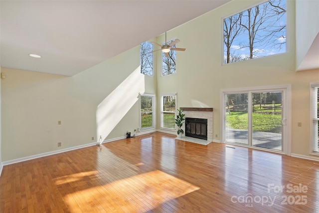 unfurnished living room with ceiling fan, a high ceiling, and light hardwood / wood-style floors