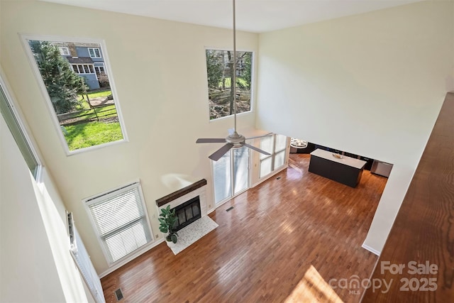 living room featuring ceiling fan, wood-type flooring, and a towering ceiling