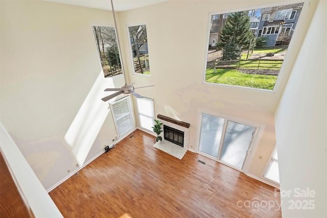 living room with a tile fireplace, ceiling fan, and wood-type flooring