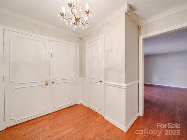 interior space featuring ornamental molding, an inviting chandelier, and light hardwood / wood-style flooring