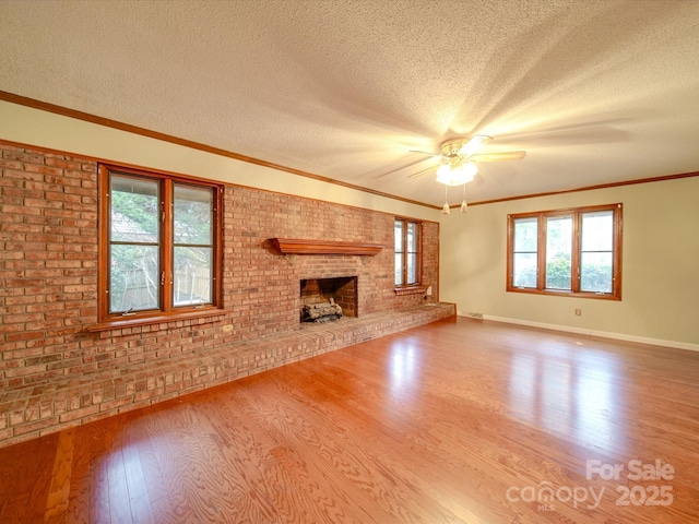 unfurnished living room featuring crown molding, hardwood / wood-style floors, a fireplace, a textured ceiling, and brick wall