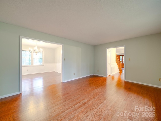 unfurnished room featuring an inviting chandelier and light hardwood / wood-style flooring