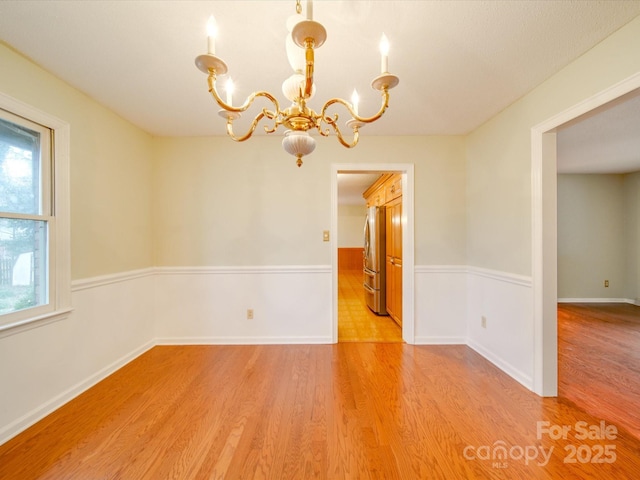 spare room with an inviting chandelier and light hardwood / wood-style flooring