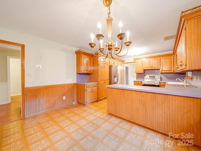 kitchen featuring sink, decorative light fixtures, appliances with stainless steel finishes, kitchen peninsula, and light parquet floors