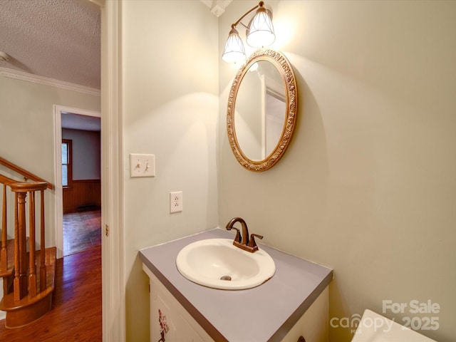 bathroom featuring hardwood / wood-style flooring, ornamental molding, vanity, and a textured ceiling