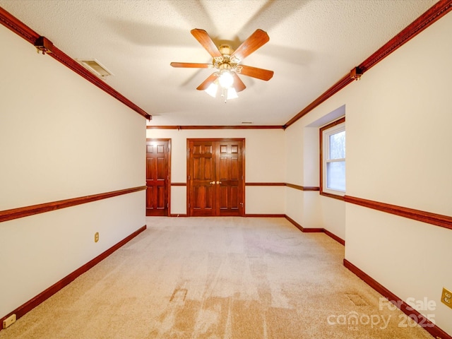 carpeted spare room featuring ceiling fan, crown molding, and a textured ceiling