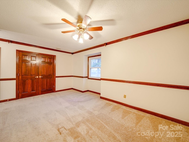 carpeted empty room with crown molding, ceiling fan, and a textured ceiling