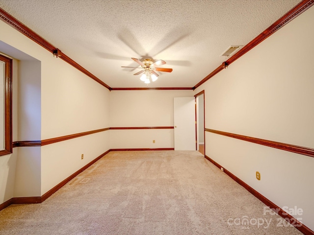 carpeted spare room featuring ceiling fan, ornamental molding, and a textured ceiling