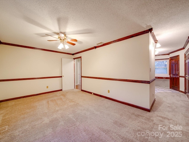 carpeted spare room featuring ceiling fan, ornamental molding, and a textured ceiling