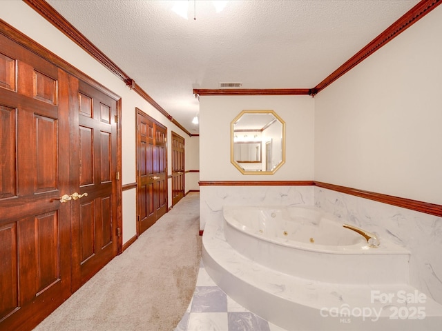 bathroom with a bath, ornamental molding, and a textured ceiling