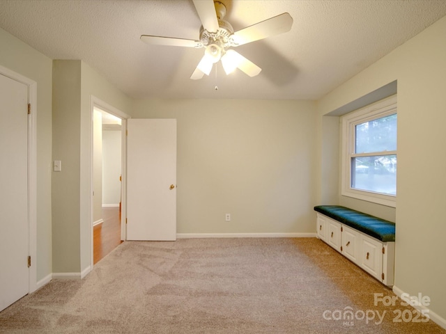 unfurnished bedroom featuring ceiling fan, light colored carpet, and a textured ceiling