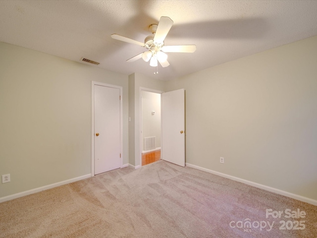 unfurnished bedroom featuring ceiling fan, light colored carpet, and a textured ceiling