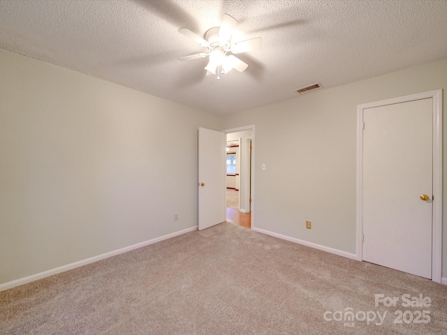 empty room featuring light carpet, a textured ceiling, and ceiling fan