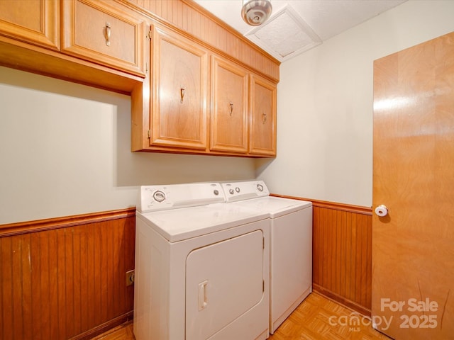 washroom featuring cabinets, light parquet flooring, separate washer and dryer, and wooden walls