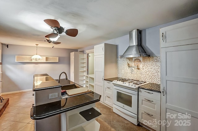 kitchen featuring tile patterned floors, sink, gas range gas stove, white cabinetry, and wall chimney range hood