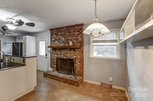 kitchen featuring ceiling fan with notable chandelier, white cabinetry, hanging light fixtures, a fireplace, and black fridge with ice dispenser