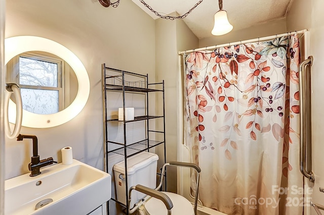 bathroom featuring a shower with curtain, toilet, and sink