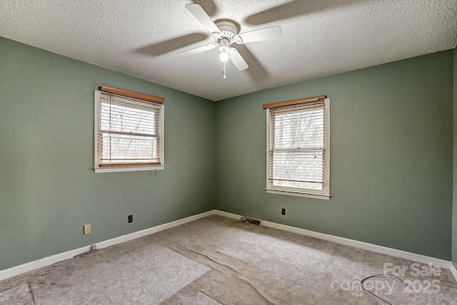 empty room featuring ceiling fan, a wealth of natural light, and a textured ceiling