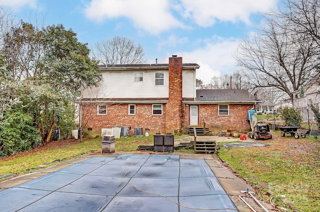 rear view of house with cooling unit, a covered pool, and a patio area