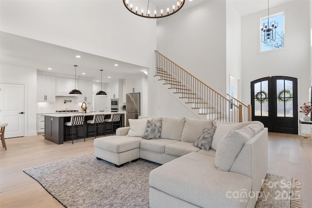 living area with recessed lighting, a notable chandelier, french doors, stairway, and light wood-type flooring