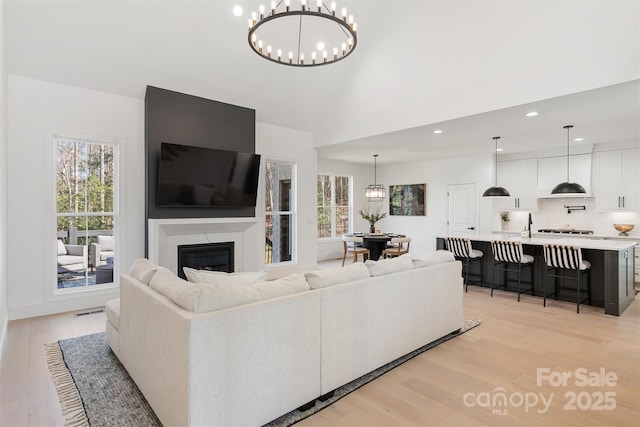 living room featuring a chandelier, a high end fireplace, light wood-type flooring, and recessed lighting