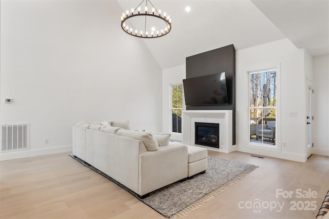 living area with light wood-style flooring, plenty of natural light, a glass covered fireplace, and visible vents