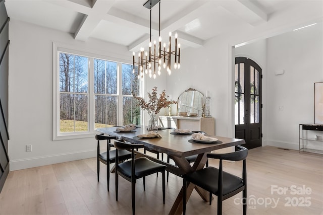 dining room with plenty of natural light, light wood finished floors, baseboards, and arched walkways