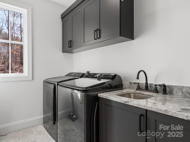 laundry area with baseboards, a sink, cabinet space, and washer and dryer