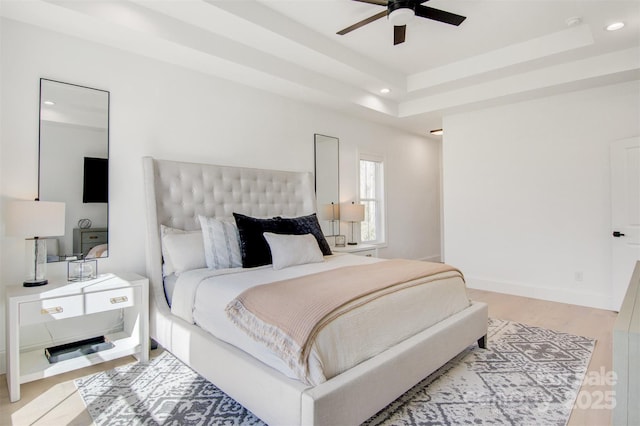 bedroom with recessed lighting, a raised ceiling, light wood-style flooring, and baseboards