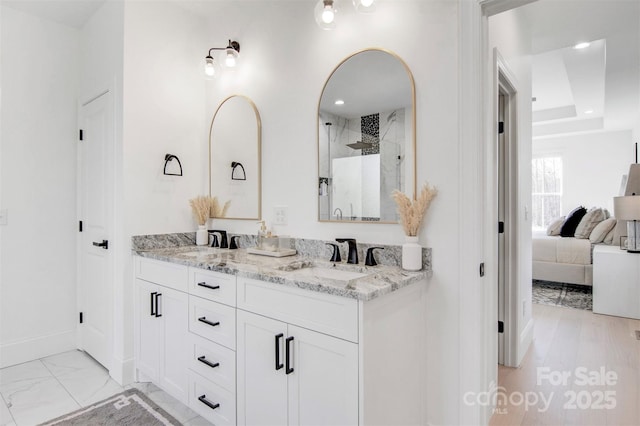 full bath featuring ensuite bathroom, marble finish floor, double vanity, and a sink