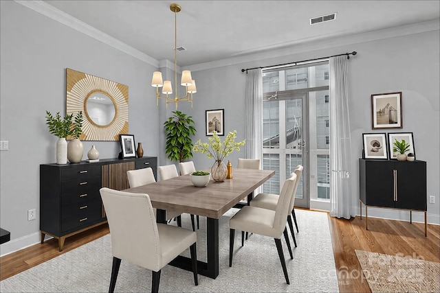 dining area featuring an inviting chandelier, light hardwood / wood-style flooring, and ornamental molding