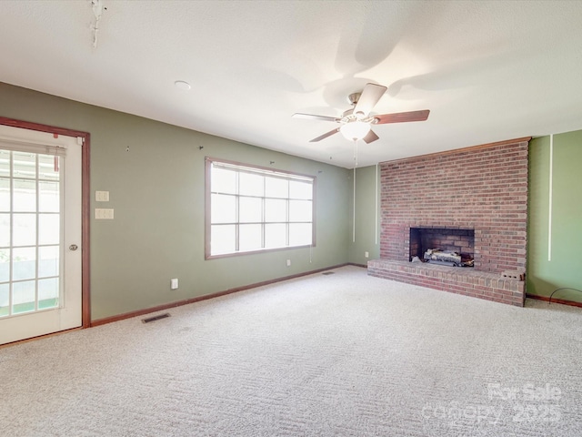 unfurnished living room featuring a fireplace, visible vents, baseboards, a ceiling fan, and carpet