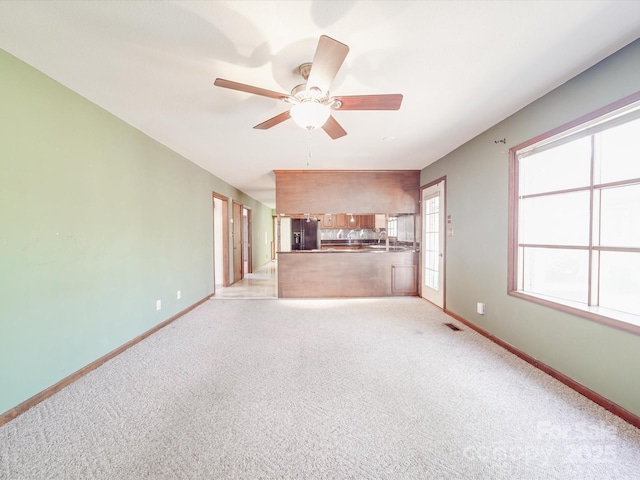 unfurnished living room with light carpet, visible vents, baseboards, and a ceiling fan