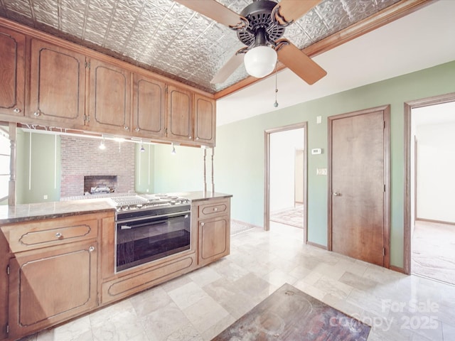 kitchen with an ornate ceiling, baseboards, ceiling fan, and stainless steel stove