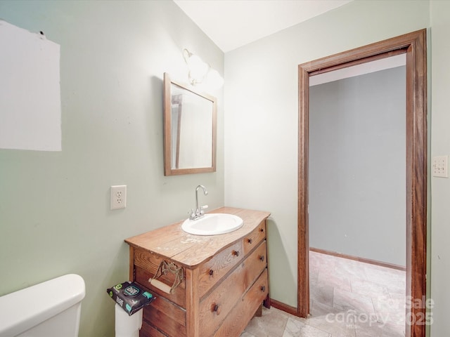 bathroom featuring baseboards, vanity, and toilet