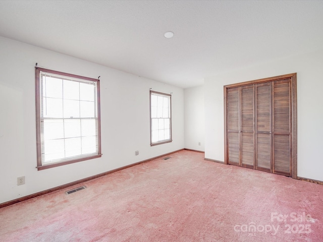 unfurnished bedroom featuring visible vents, baseboards, and light colored carpet