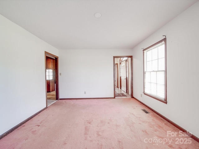 unfurnished room with baseboards, visible vents, and light colored carpet