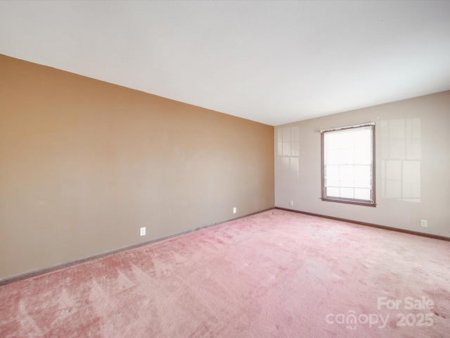 carpeted empty room featuring baseboards