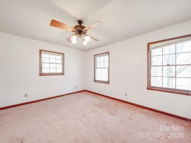 spare room with light colored carpet, ceiling fan, and baseboards