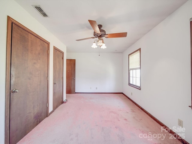 unfurnished bedroom featuring baseboards, visible vents, ceiling fan, and light colored carpet