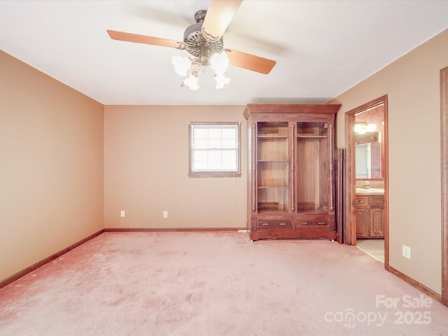 unfurnished bedroom featuring light carpet, ceiling fan, baseboards, and ensuite bathroom