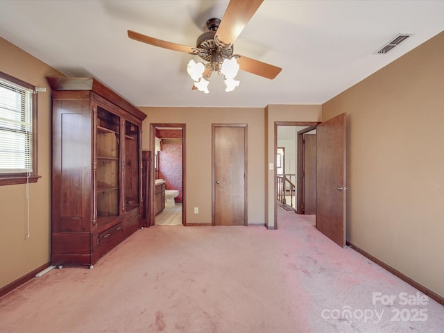 unfurnished bedroom featuring ensuite bath, baseboards, visible vents, and light colored carpet