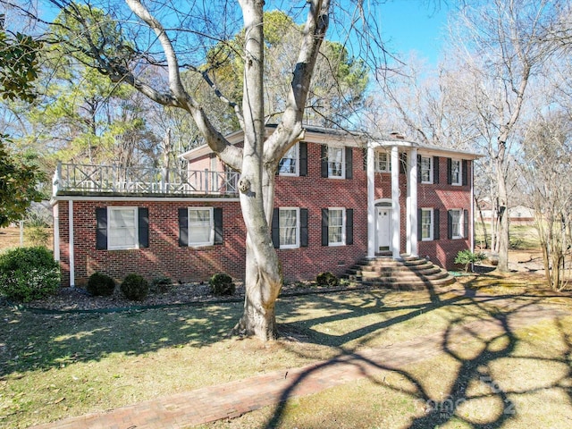 greek revival inspired property featuring a front yard and brick siding