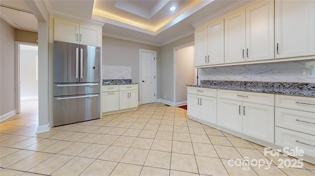 kitchen featuring tasteful backsplash, light tile patterned floors, stainless steel refrigerator, and dark stone counters